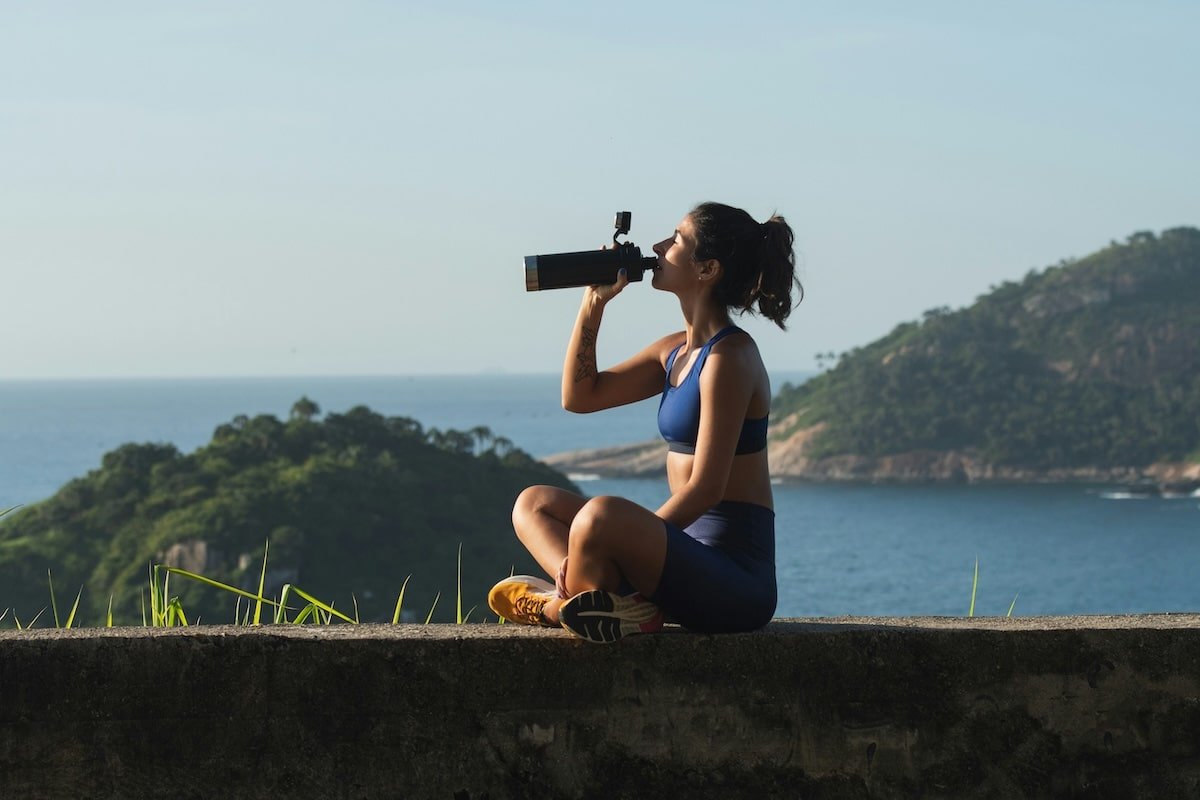 Une femme s'hydrate correctement au bord de l'océan.